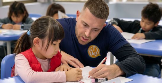 Let's Talk! 外籍英語老師俯身協助小學生練習英語寫作，展現個別化全外師教學