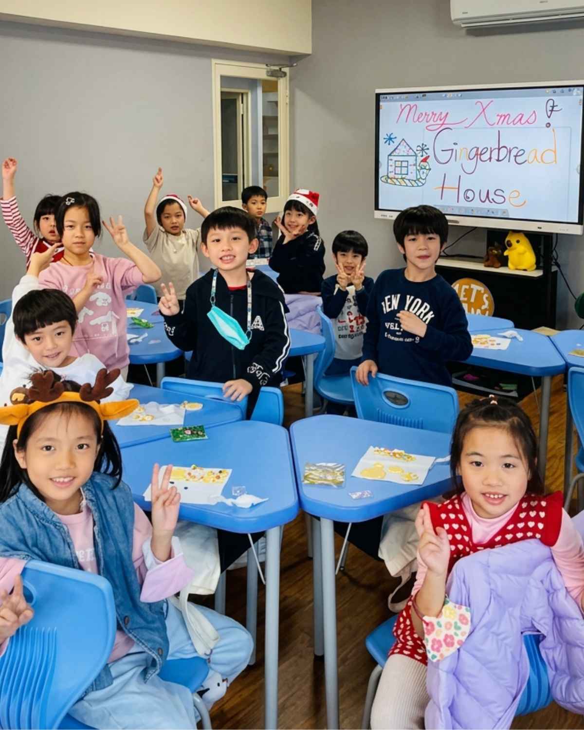 Let's Talk! 學生在聖誕節主題英語課堂中開心合影，黑板上寫有薑餅屋英語活動主題